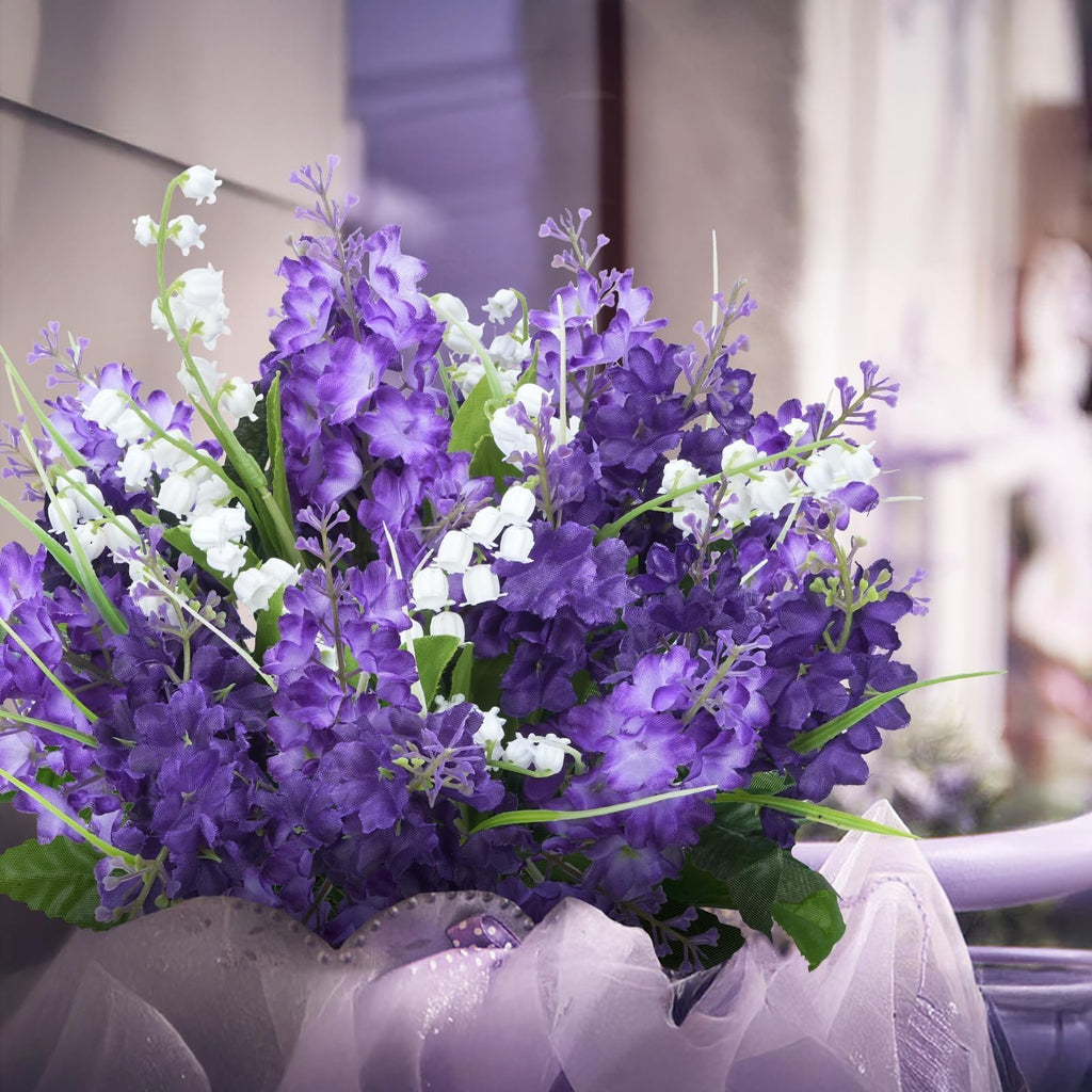 Close-up of a purple and white artificial flower bouquet with sheer purple ribbon at the base.