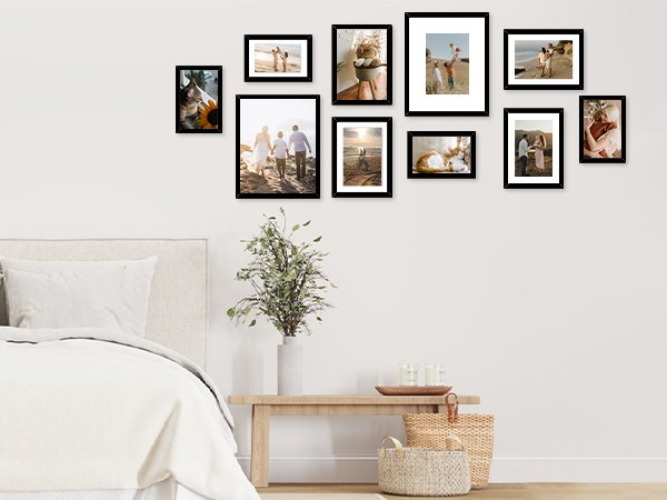 Collage of ten black picture frames displaying family photos and beach scenes, arranged on a wall above a bed.