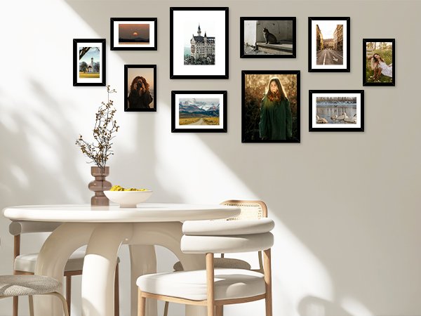 Collage of black picture frames displaying various scenes on a wall above a dining table.