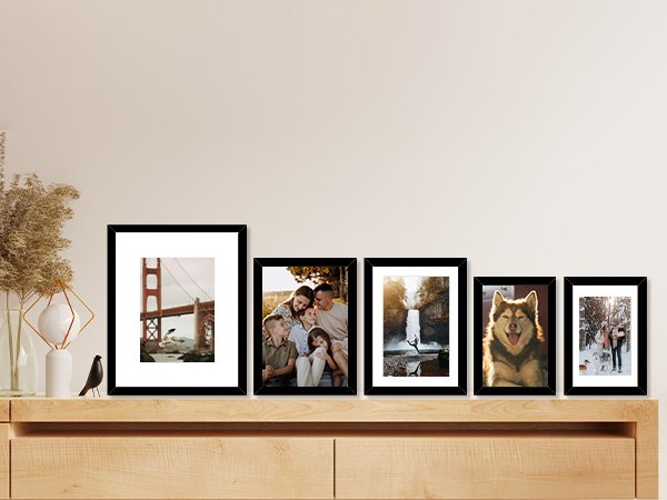 Collage of five black picture frames displaying various scenes including a bridge, family, waterfall, dog, and winter landscape.