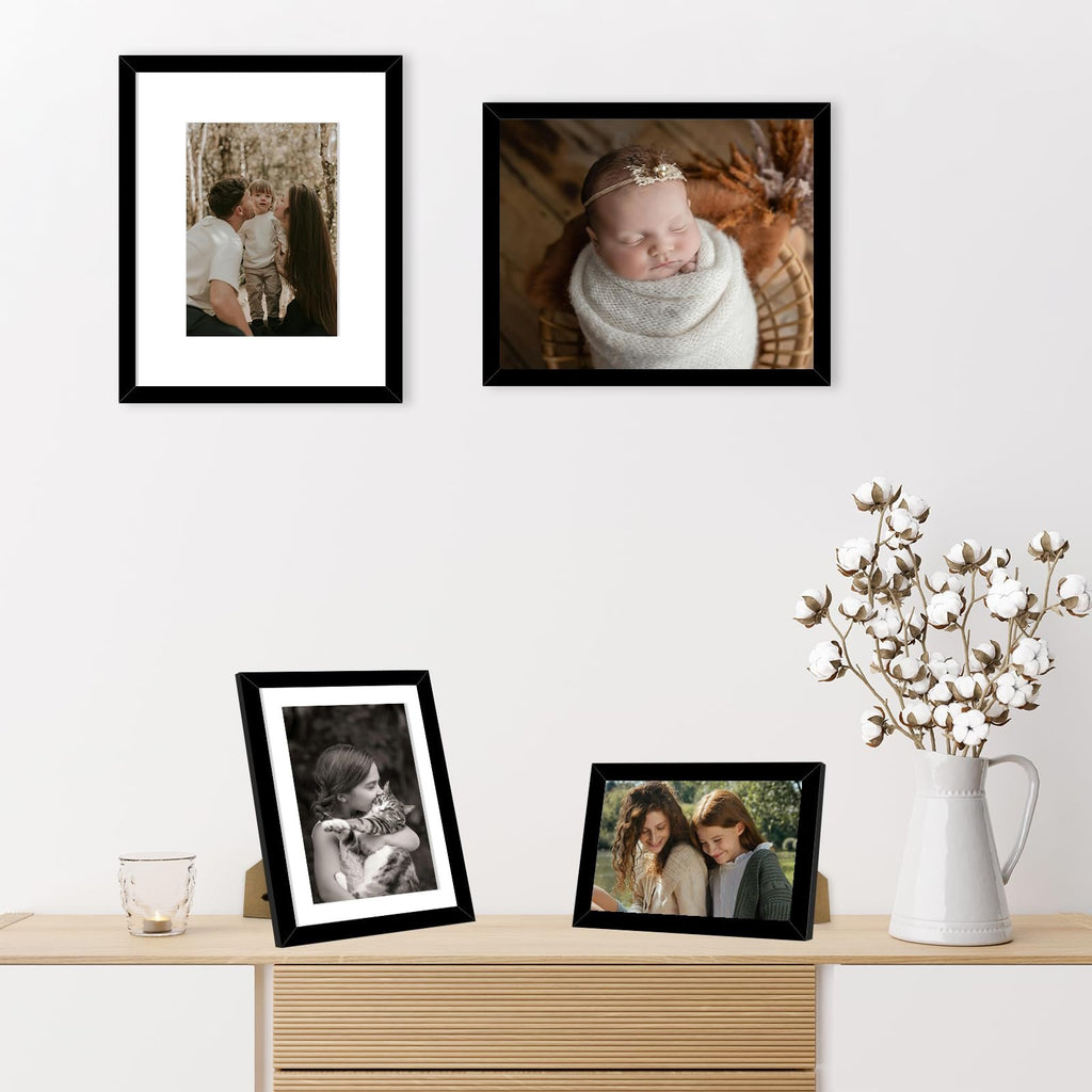 Four black collage picture frames displayed on a shelf with a vase of cotton branches