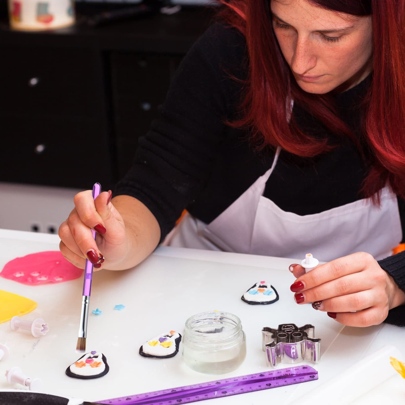 Woman decorating fondant penguins with a brush and edible paint