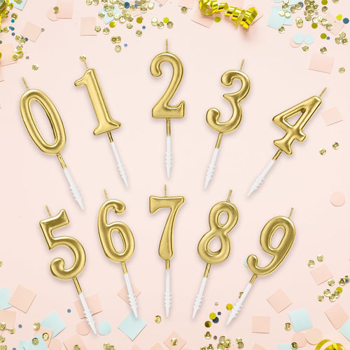 Ten gold numeral birthday candles, 0 through 9, arranged on a pink background with confetti and streamers.