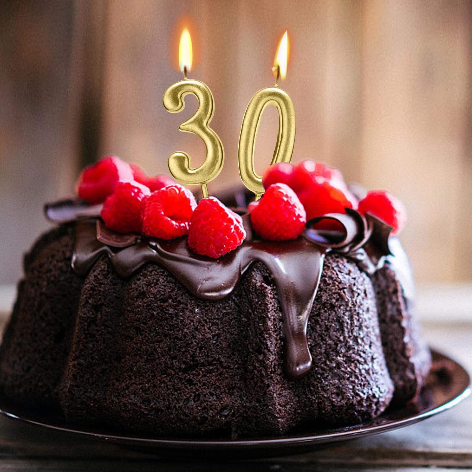 Gold numeral birthday candles '30' on a chocolate cake with raspberries and chocolate drizzle