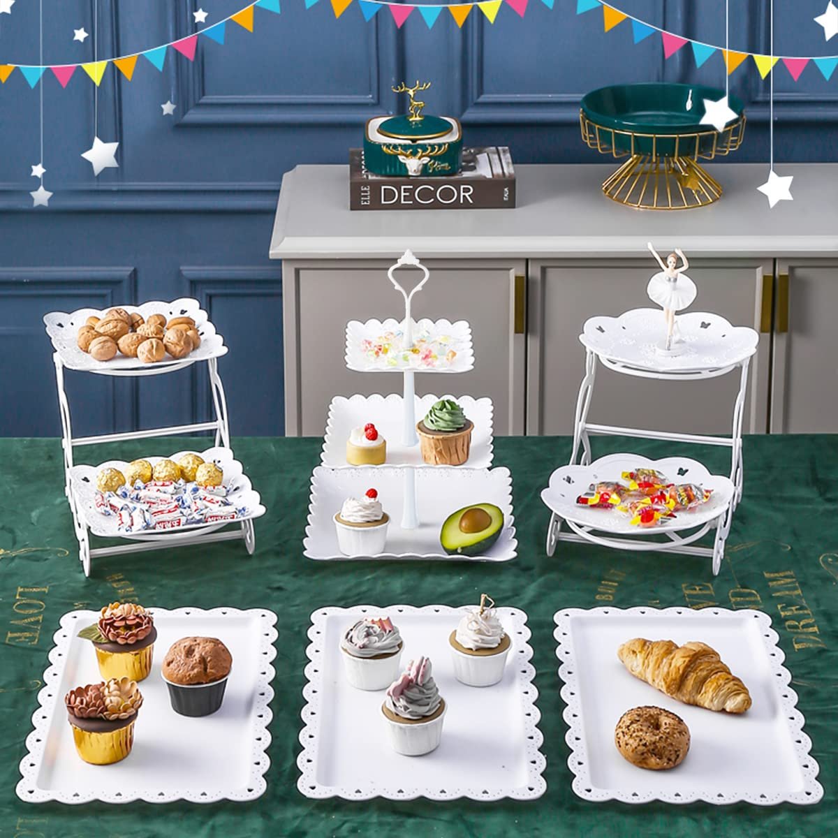 Dessert table display set with tiered stands and serving trays filled with cupcakes, pastries, and candies.
