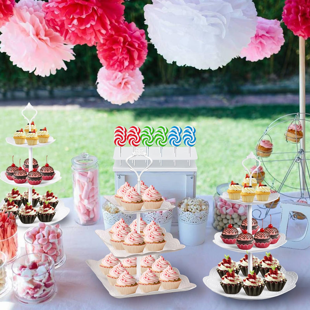 Dessert table display with cupcakes, candy, and cake stands, decorated with paper pom-poms.