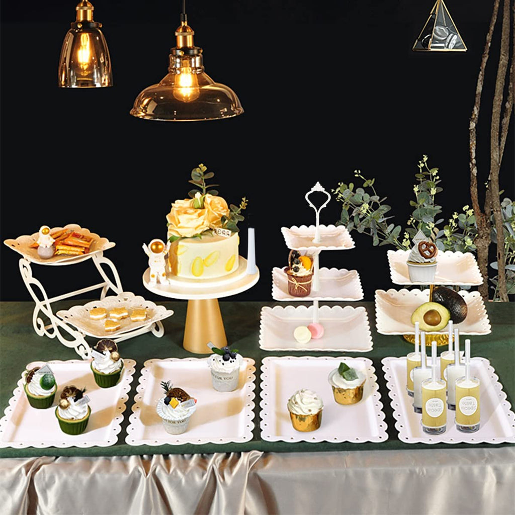 Dessert table display set with cake stands and serving trays filled with cupcakes, macarons, and drinks.