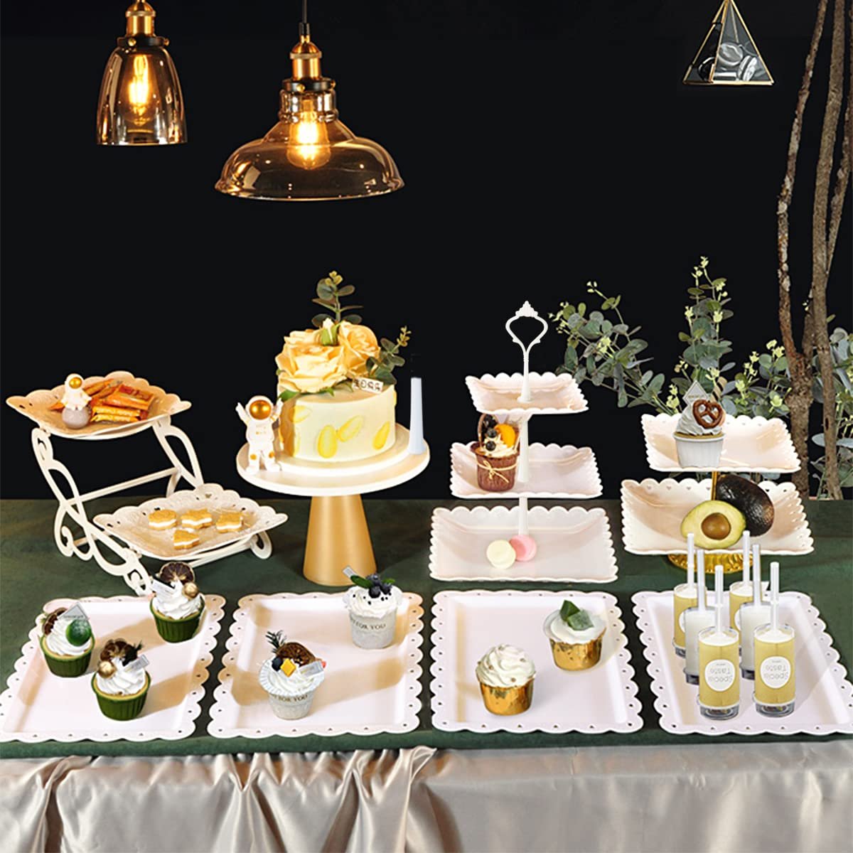 Dessert table display set with cake stands and serving trays filled with cupcakes, macarons, and drinks.