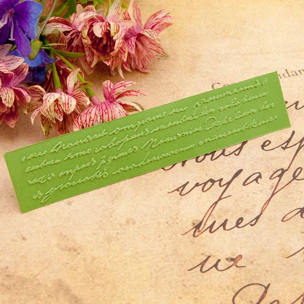 Green plastic embossing folder with script text pattern, next to pink and blue flowers.