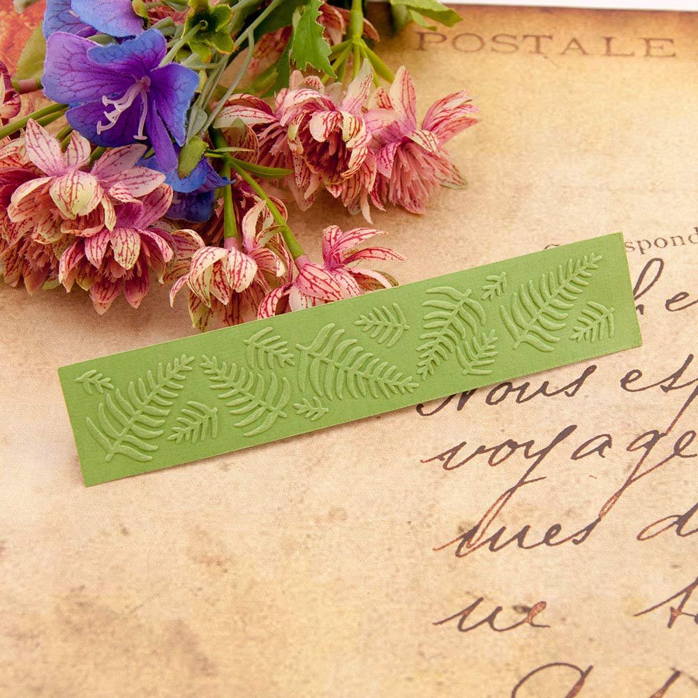 Green plastic embossing folder with fern leaf pattern, displayed with artificial flowers and vintage script background.