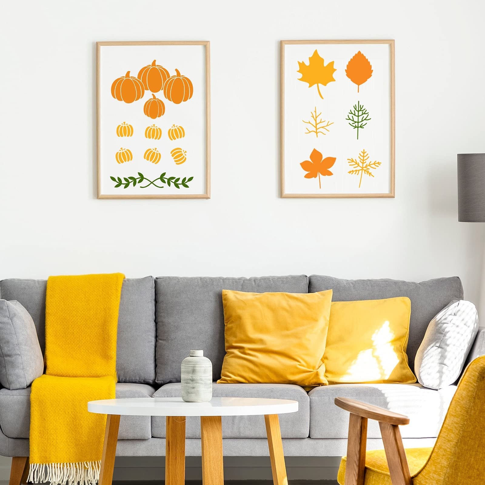 Two framed autumn-themed stencils displayed on a wall above a gray sofa with yellow accents.