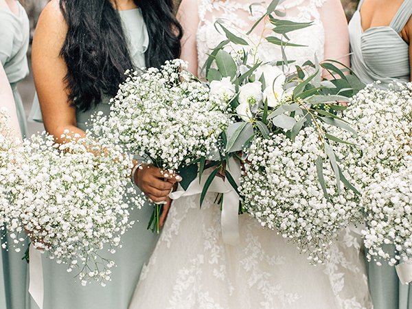 Bride and bridesmaids holding bouquets of white baby's breath and eucalyptus at a wedding.