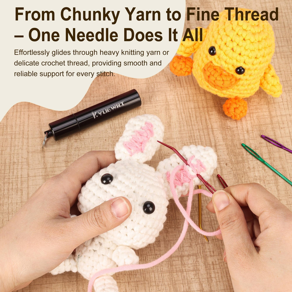 Hands using a large-eye bent needle to stitch a pink yarn onto a white crocheted bunny, with a yellow duck toy and storage tube in background.