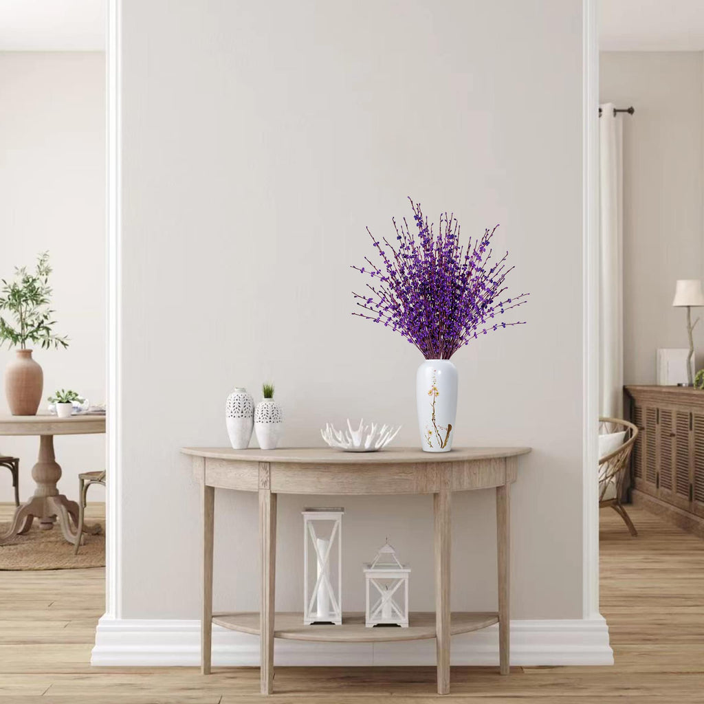 A bouquet of dark purple artificial jasmine flowers in a white vase on a console table.