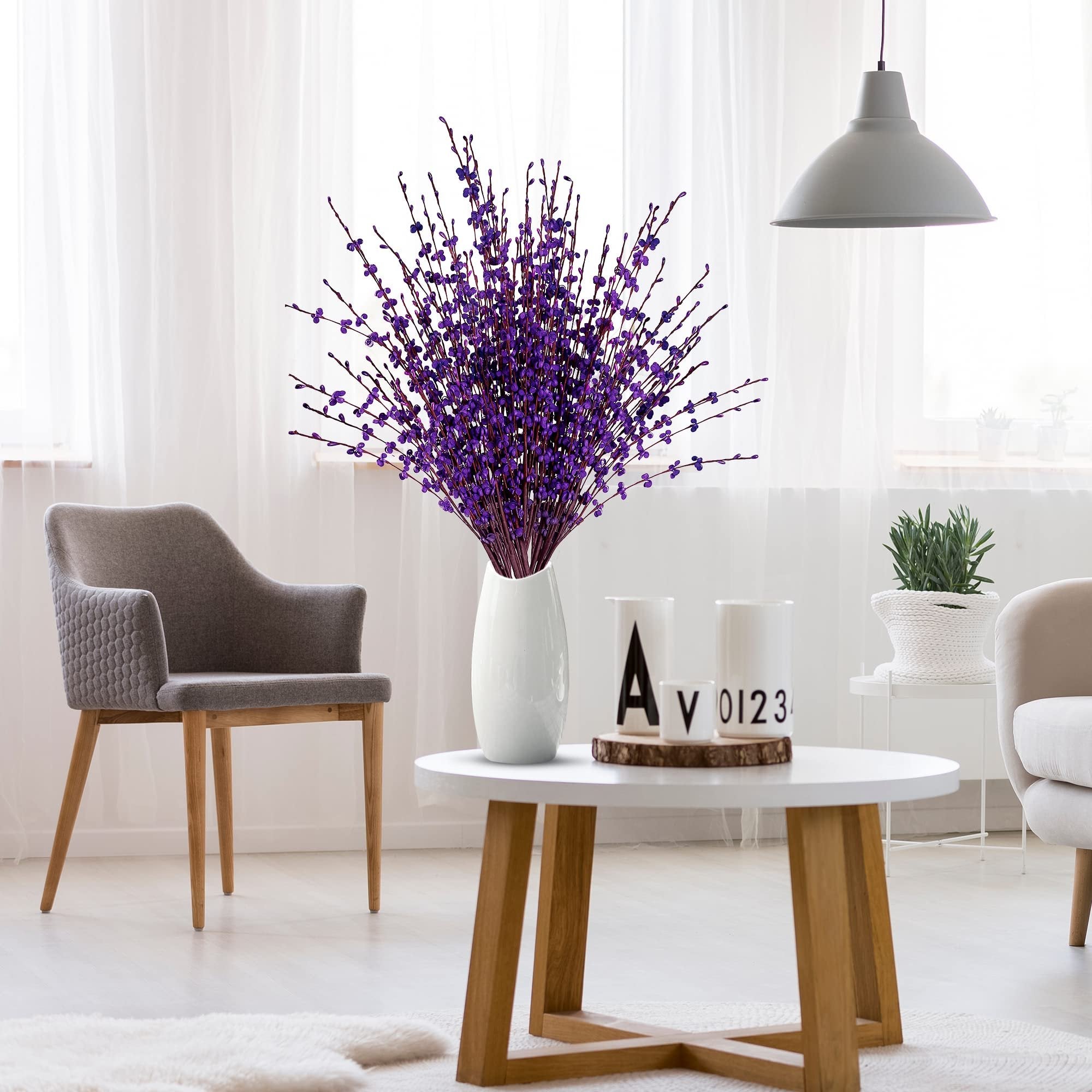 Bouquet of dark purple artificial jasmine flowers in a white vase on a coffee table in a living room setting.