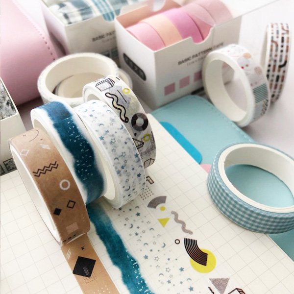 Assortment of decorative washi tape rolls with various patterns including geometric shapes, stars, and watercolor effects.