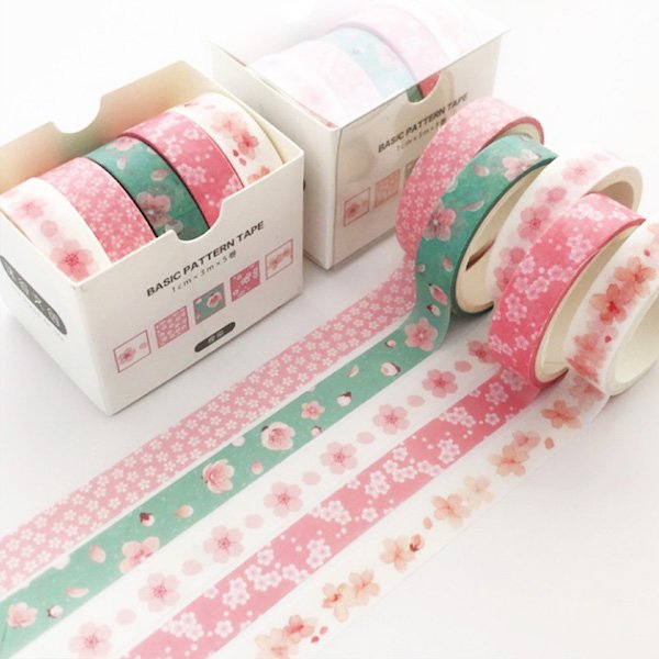 Set of decorative washi tapes with cherry blossom patterns, some in boxes and some unrolled.