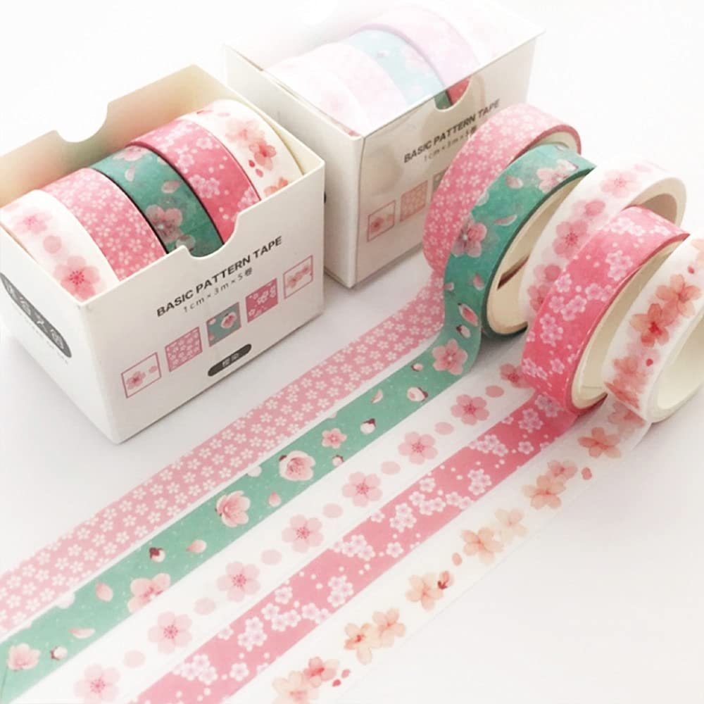 Rolls of decorative washi tape with cherry blossom patterns, some unrolled on a white surface.