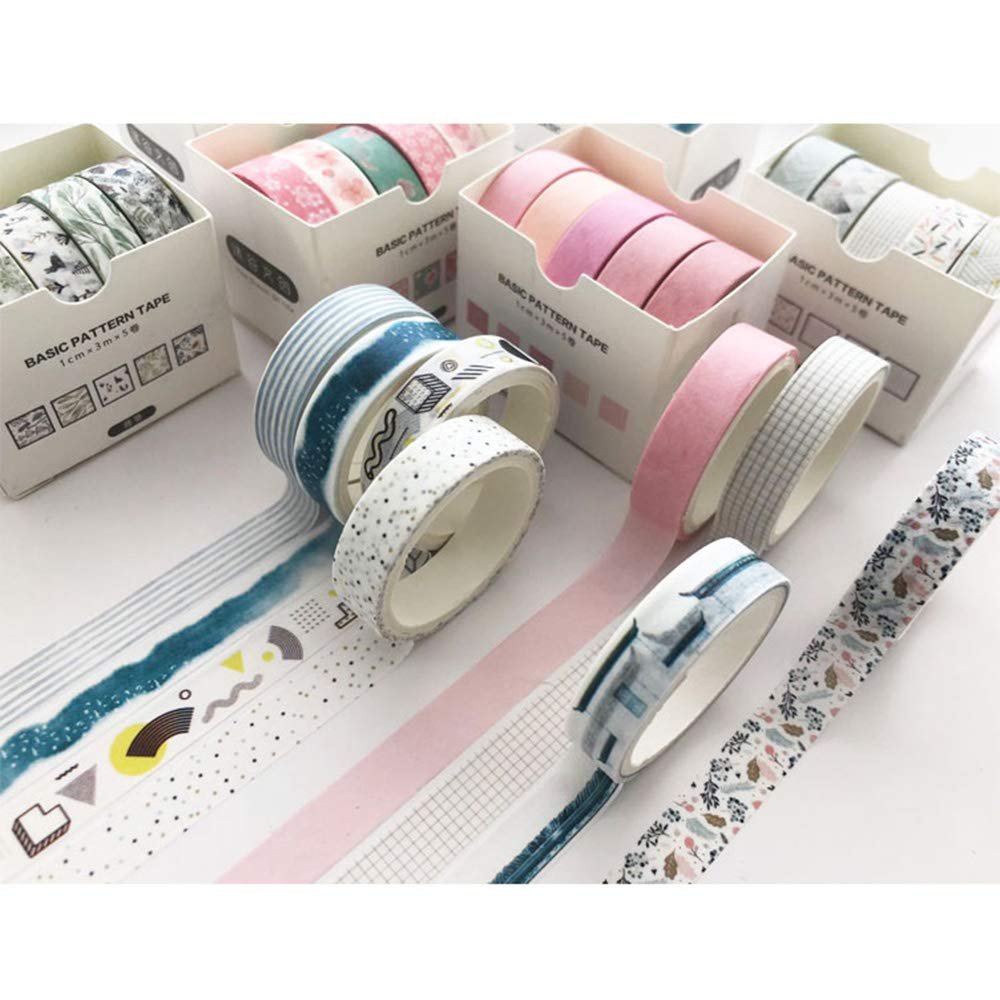 Assortment of decorative washi tape rolls with various patterns and solid colors, displayed in boxes and unrolled on a white surface.