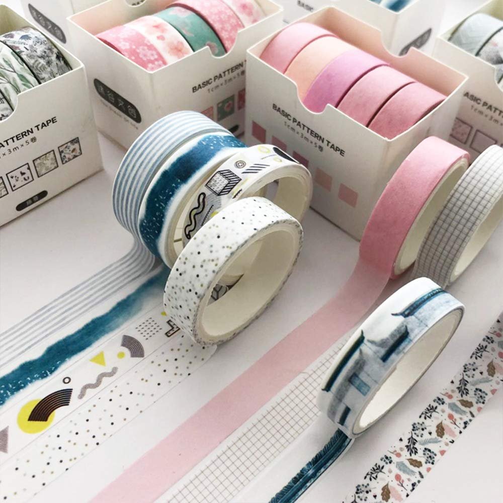 Assortment of decorative washi tape rolls with various patterns and solid colors, some unspooling onto a surface.
