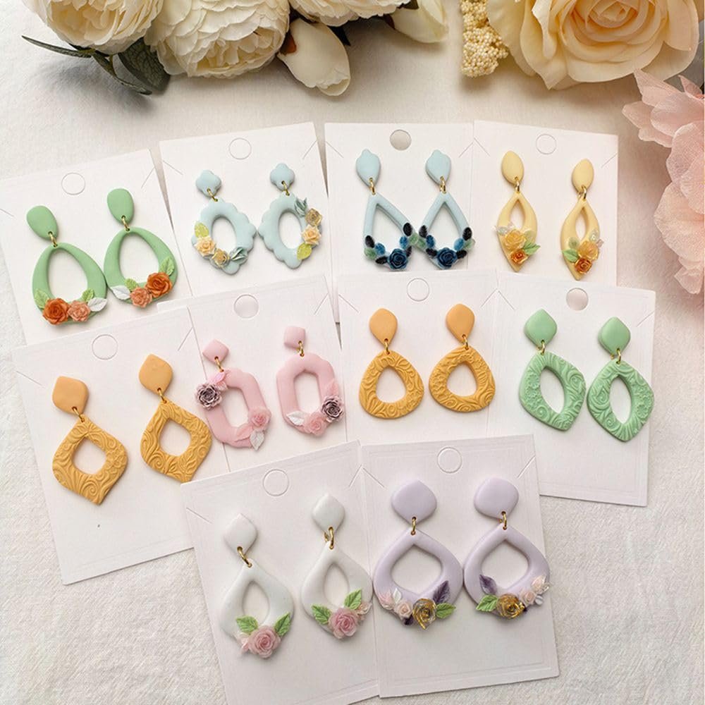 Assortment of polymer clay dangle earrings with floral embellishments, displayed on white cards.
