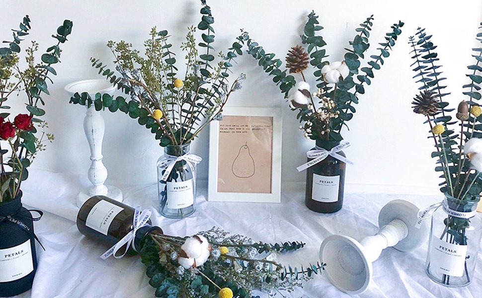 Assortment of dried eucalyptus stems and floral arrangements in vases and on a table
