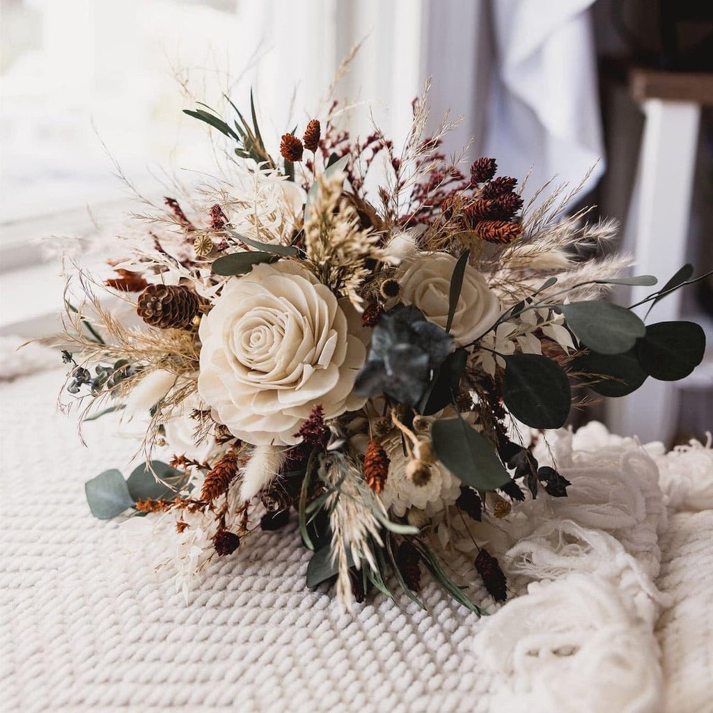 Dried eucalyptus bouquet with sola wood flowers and pinecones on a textured white blanket