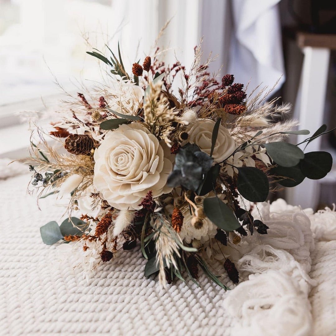 Dried eucalyptus bouquet with sola wood flowers and pinecones on a textured white blanket
