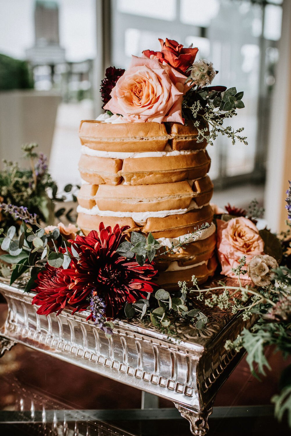 Naked waffle cake decorated with roses and dahlias on a silver platter