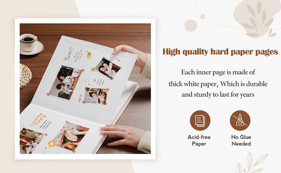 Open linen hardcover scrapbook album with photos and handwritten notes on thick white paper pages.