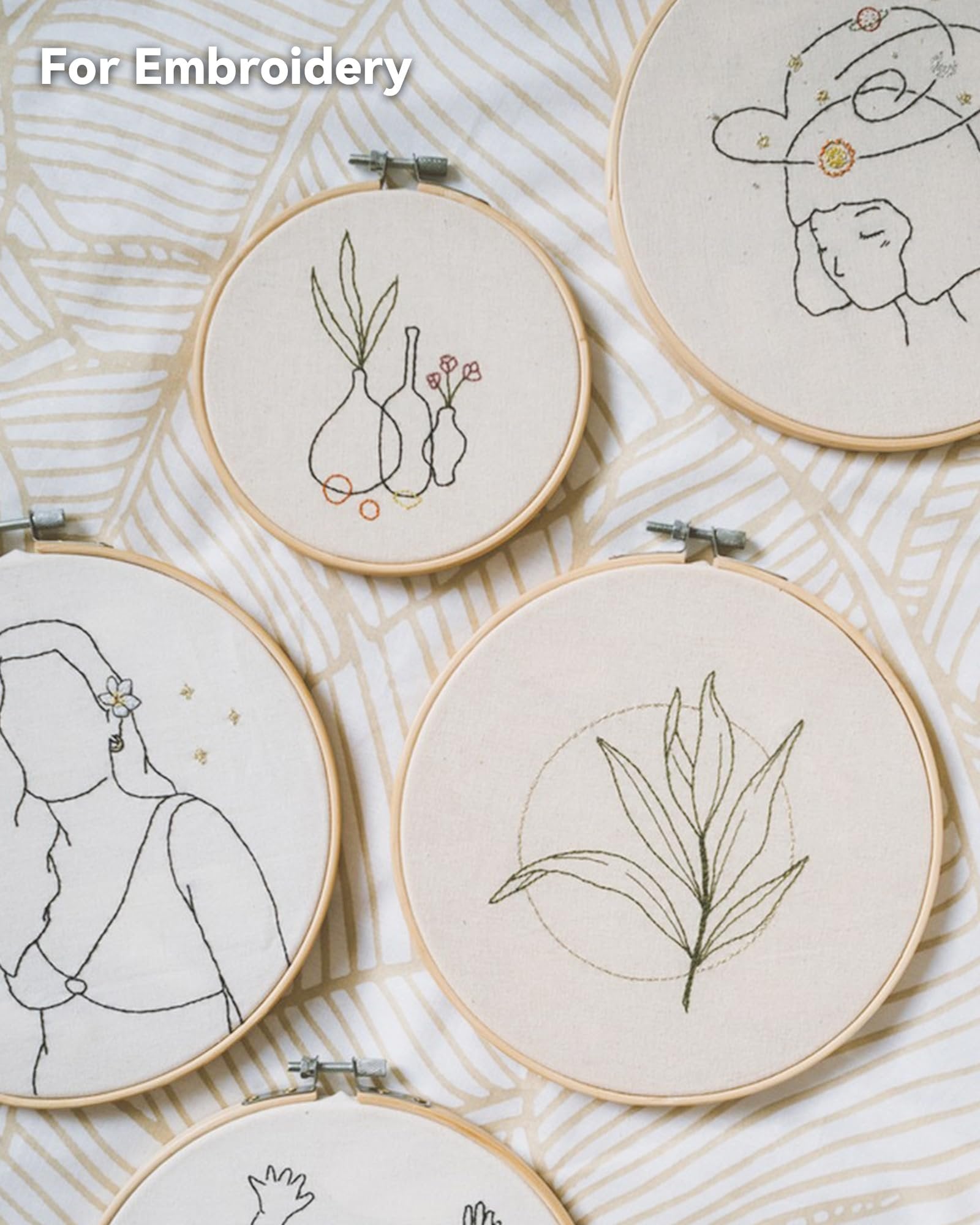 Embroidery hoops with line art designs of vases, a woman's profile, and a plant leaf.