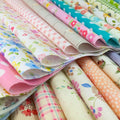 Stack of assorted floral, polka dot, stripe, and gingham fabric squares for crafts