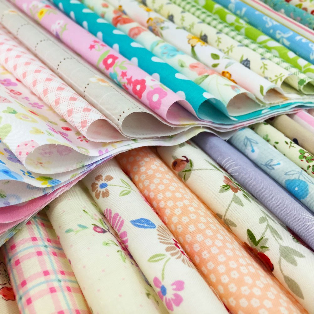 Stack of precut floral and printed quilting fabric squares in various pastel colors and patterns.