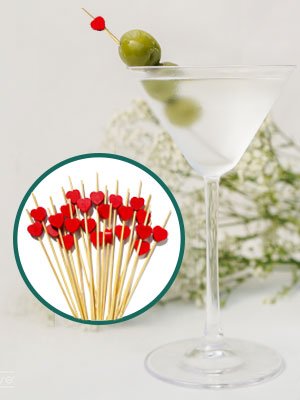 Bamboo cocktail picks with red heart tops in a martini glass with olives and a circular inset of picks