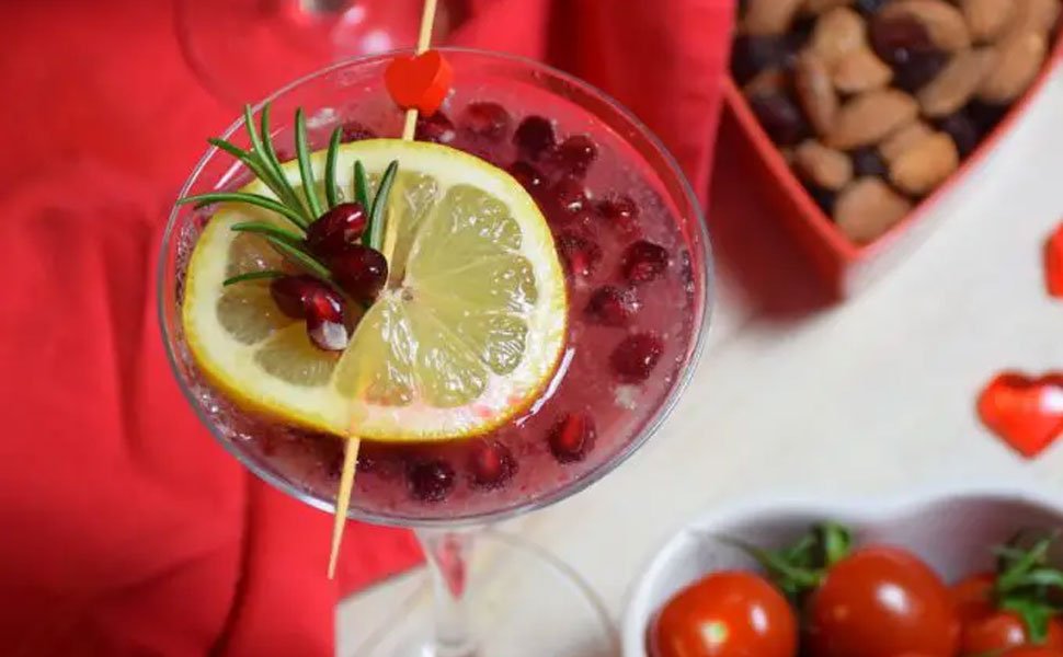 Bamboo cocktail pick with red heart top in a drink with lemon and pomegranate seeds