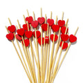 A fan of bamboo cocktail picks with red heart tops on a white background.