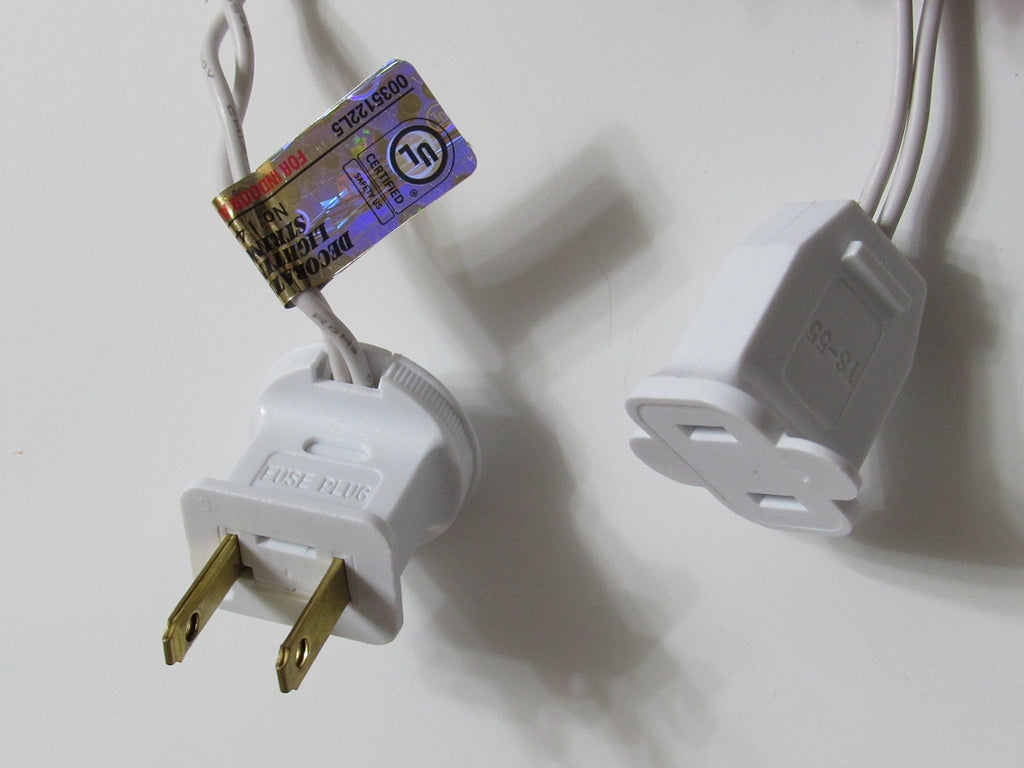 Close-up of two white electrical plugs for string lights, one labeled 'FUSE PLUG' and the other 'TS-55', with a UL certification tag.