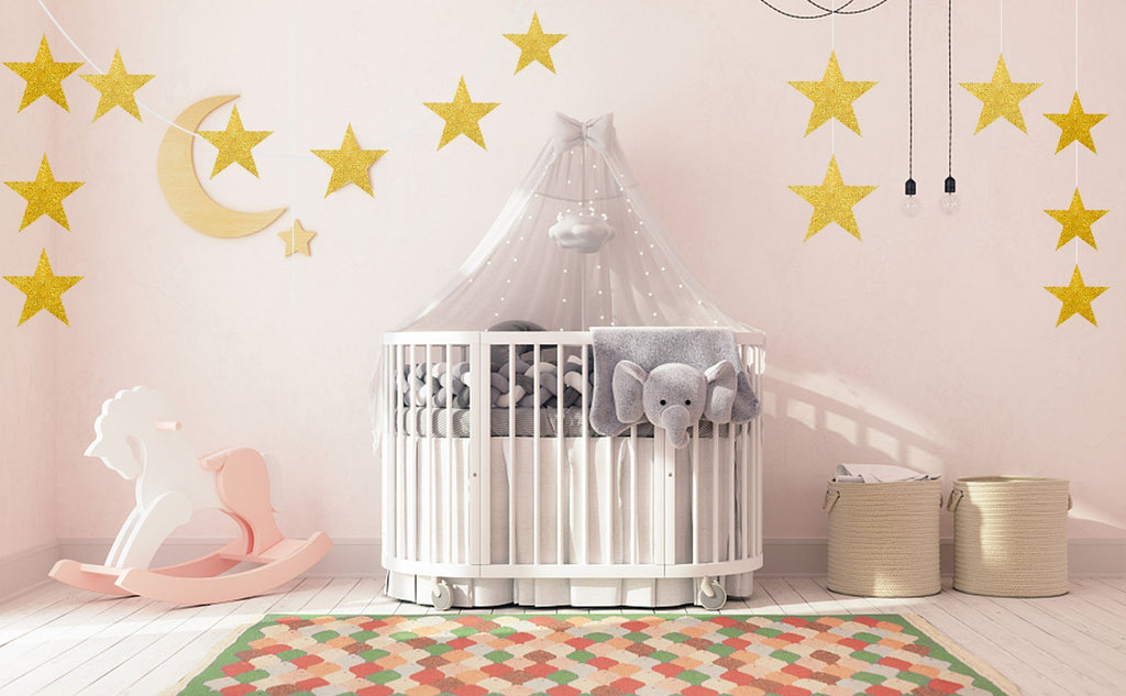 Glitter gold star cutouts and a crescent moon decoration above a crib in a nursery.