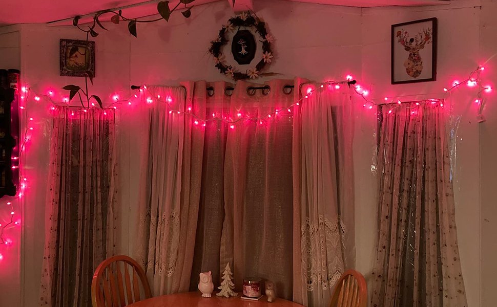 Pink string lights draped across a wall with curtains and framed art.