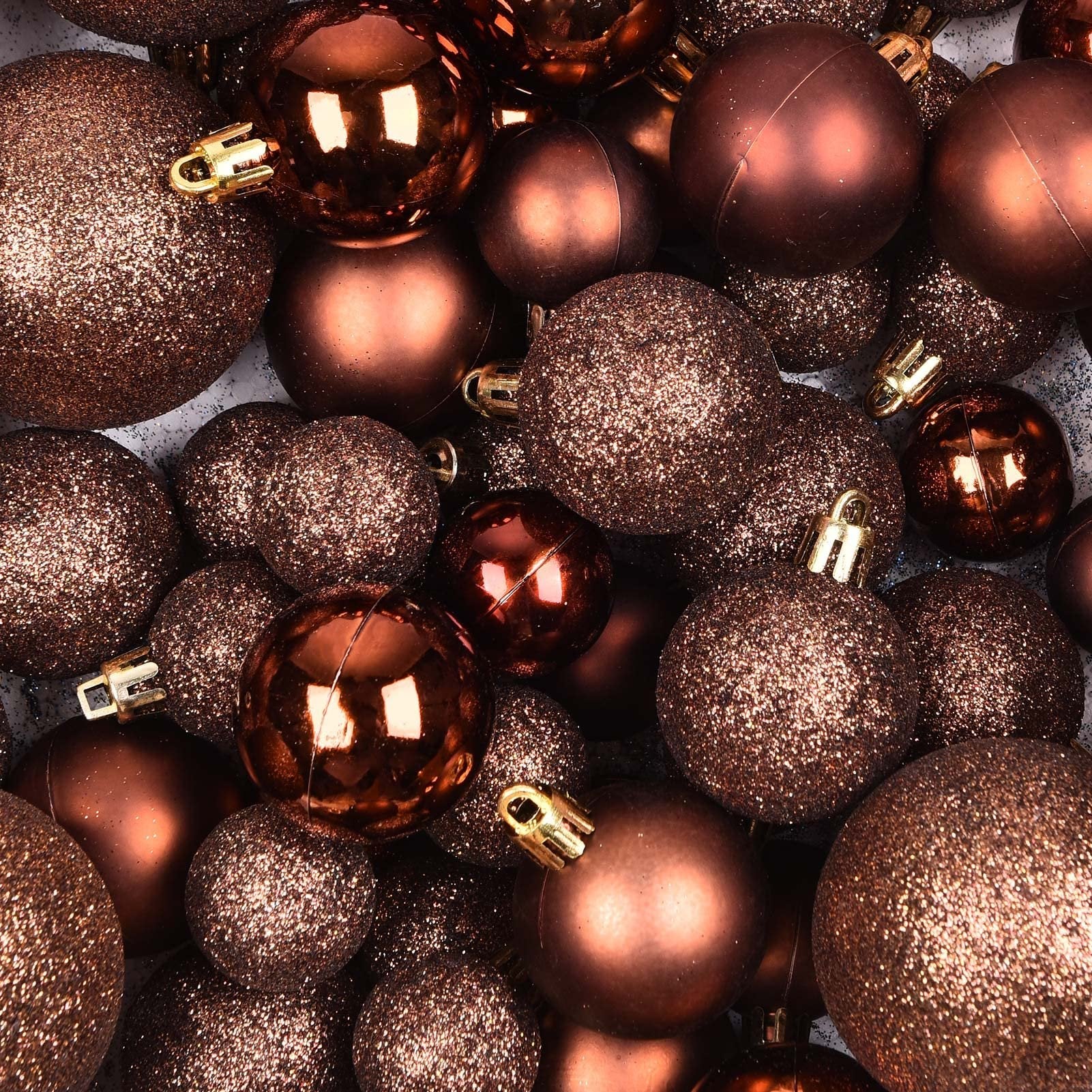Close-up overhead view of assorted brown Christmas ball ornaments, some glittery and some smooth, with gold caps.