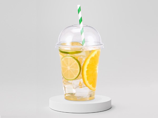 Clear plastic cup with dome lid filled with ice, citrus slices, and a green striped straw.