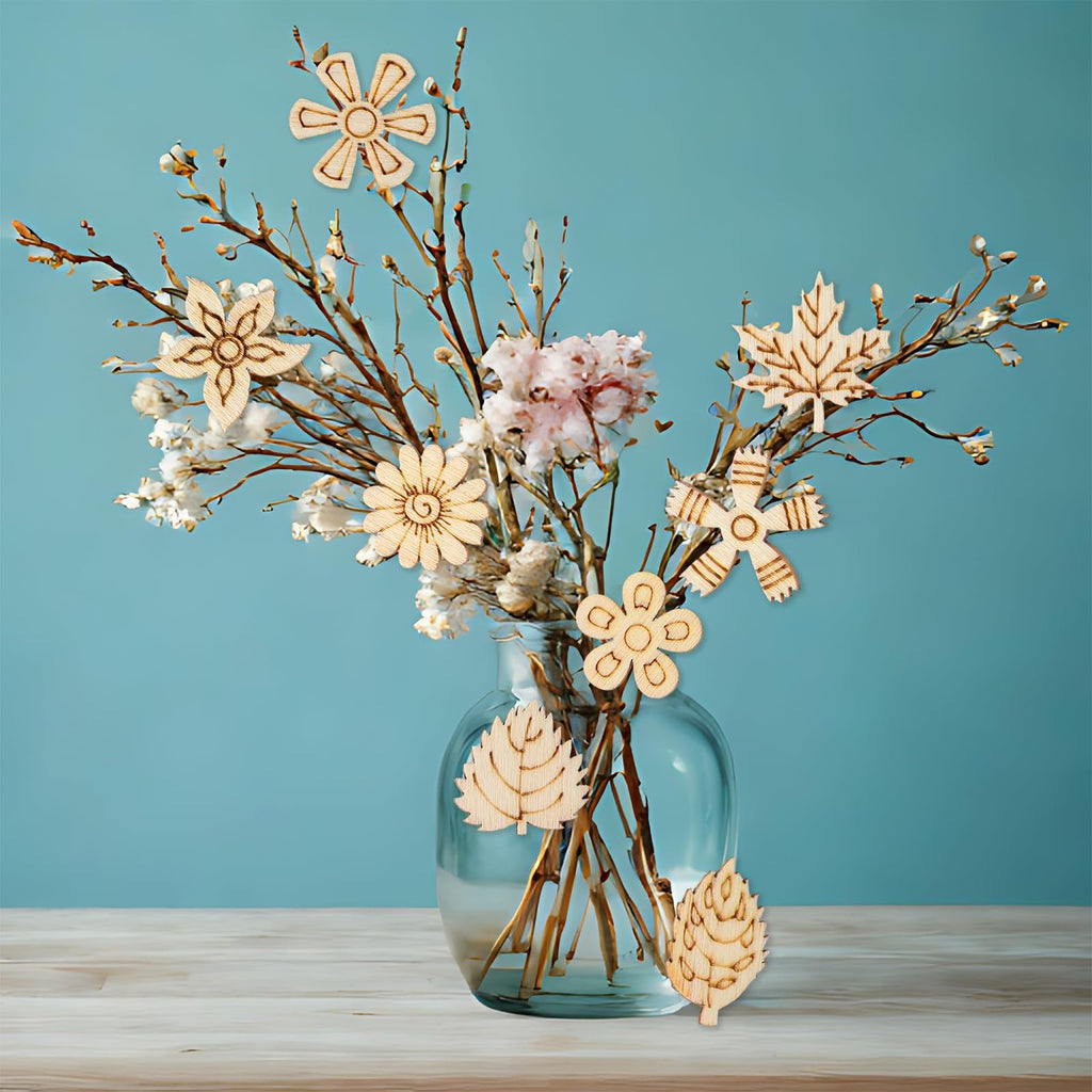 Wooden flower and leaf craft cutouts arranged in a vase with branches and dried flowers against a blue background.