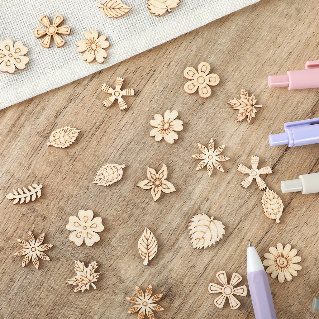 Assortment of 20mm unfinished wooden flower and leaf craft cutouts scattered on a wooden surface.