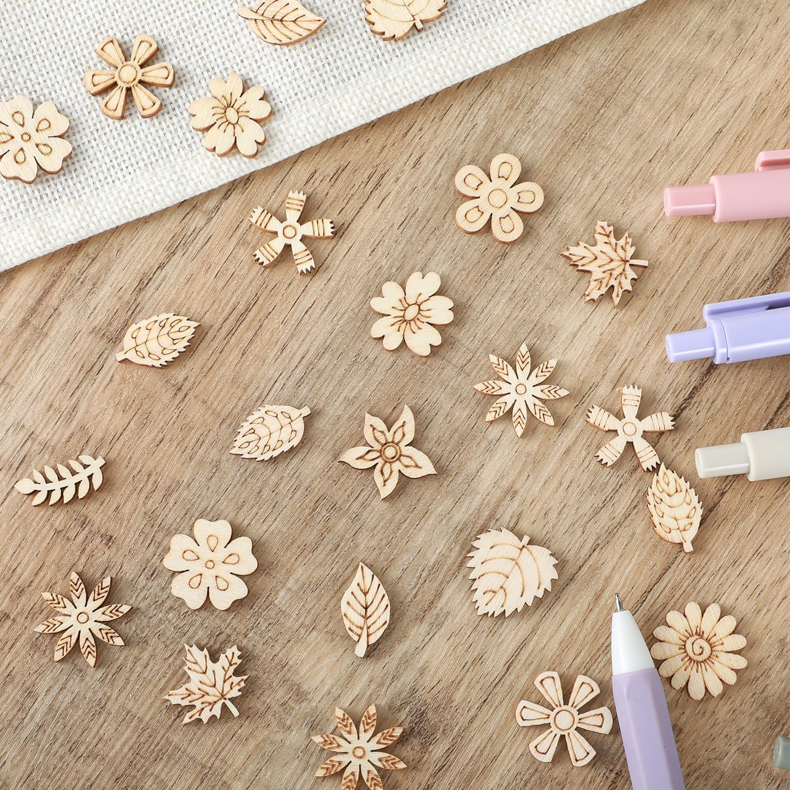 Assortment of 20mm unfinished wooden flower and leaf craft cutouts scattered on a wooden surface.