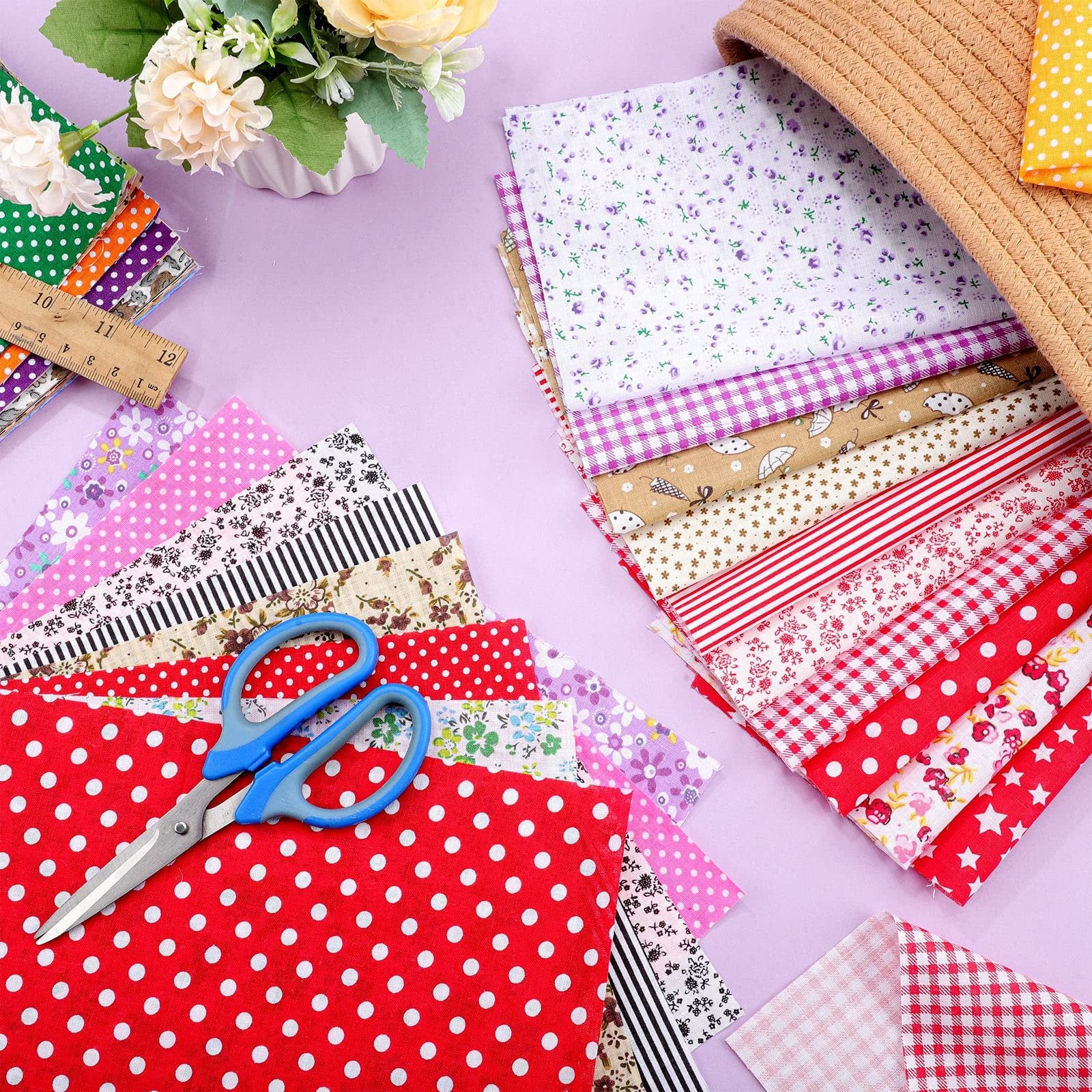 Stack of multicolor floral and patterned fabric squares with blue scissors and a ruler on a lavender background.