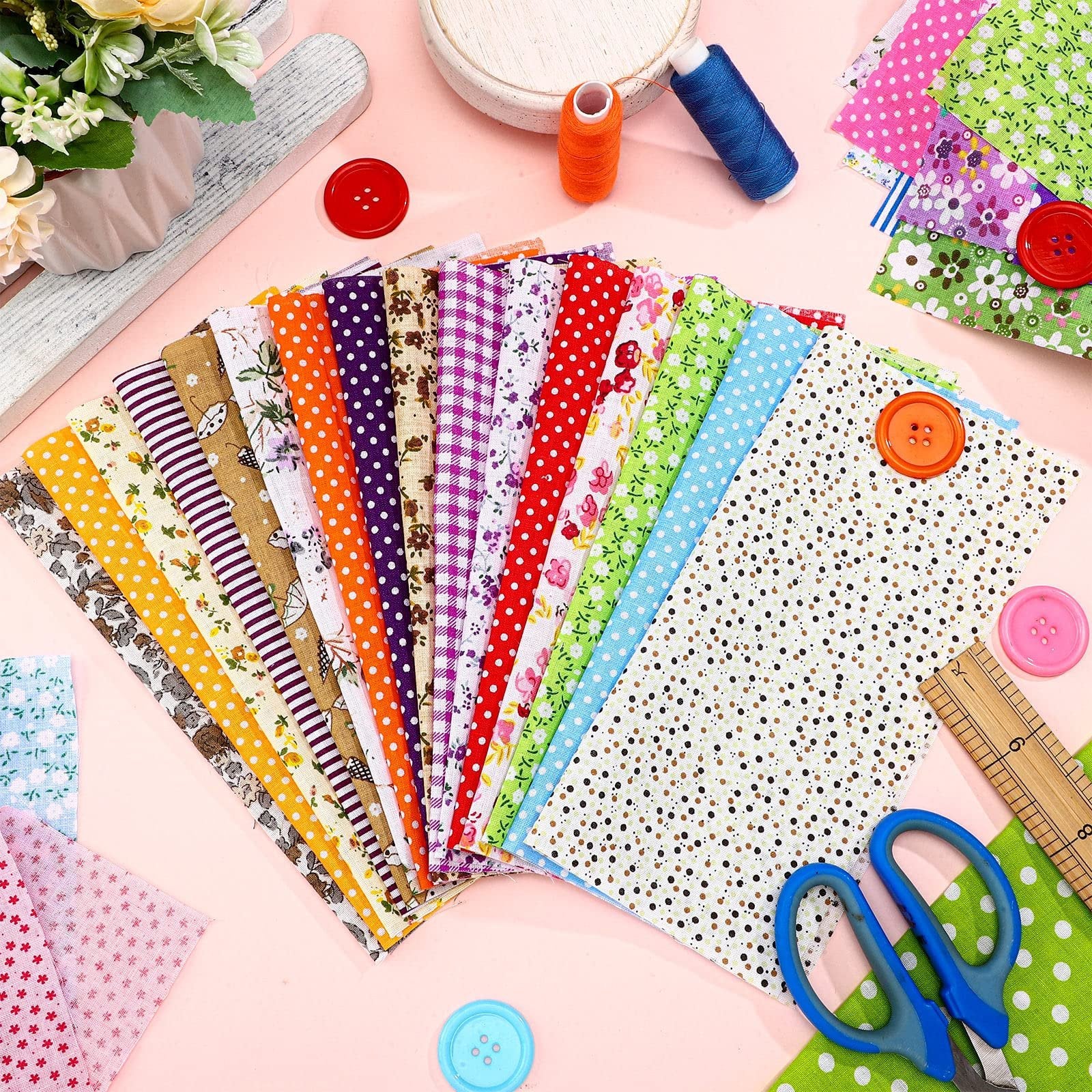Assortment of colorful floral and patterned cotton fabric squares with sewing notions like buttons, thread, and a ruler.