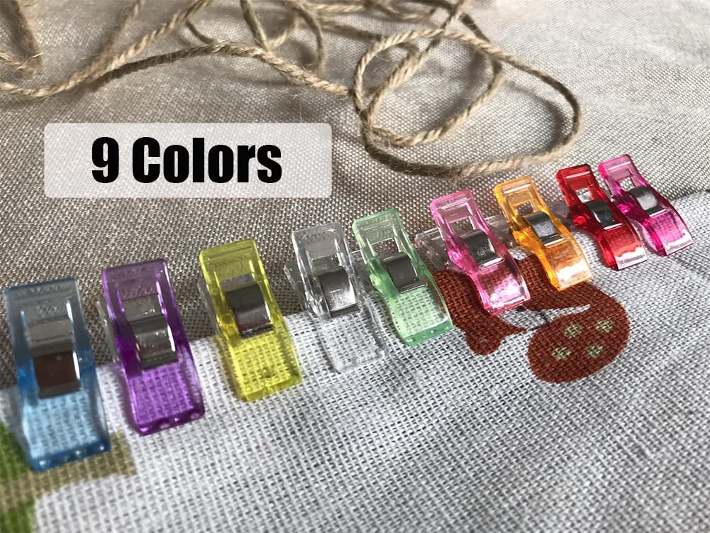 Assorted colorful sewing clips arranged on fabric with twine in the background.