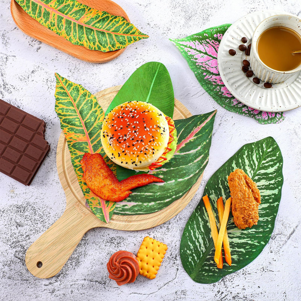 Tropical leaf parchment paper serving as placemats for food items like a burger, chicken wing, fries, chocolate, and coffee.
