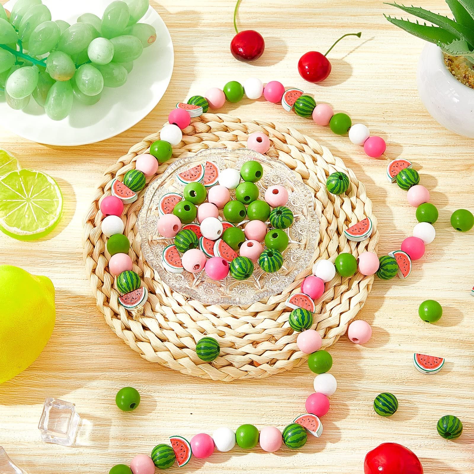 Watermelon and solid colored wooden beads arranged on a wooden surface with fruit props