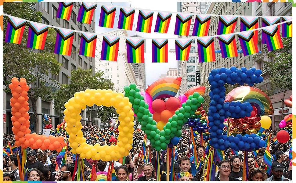 Rainbow Pride flag bunting strung across a street parade with large balloon letters spelling LOVE.